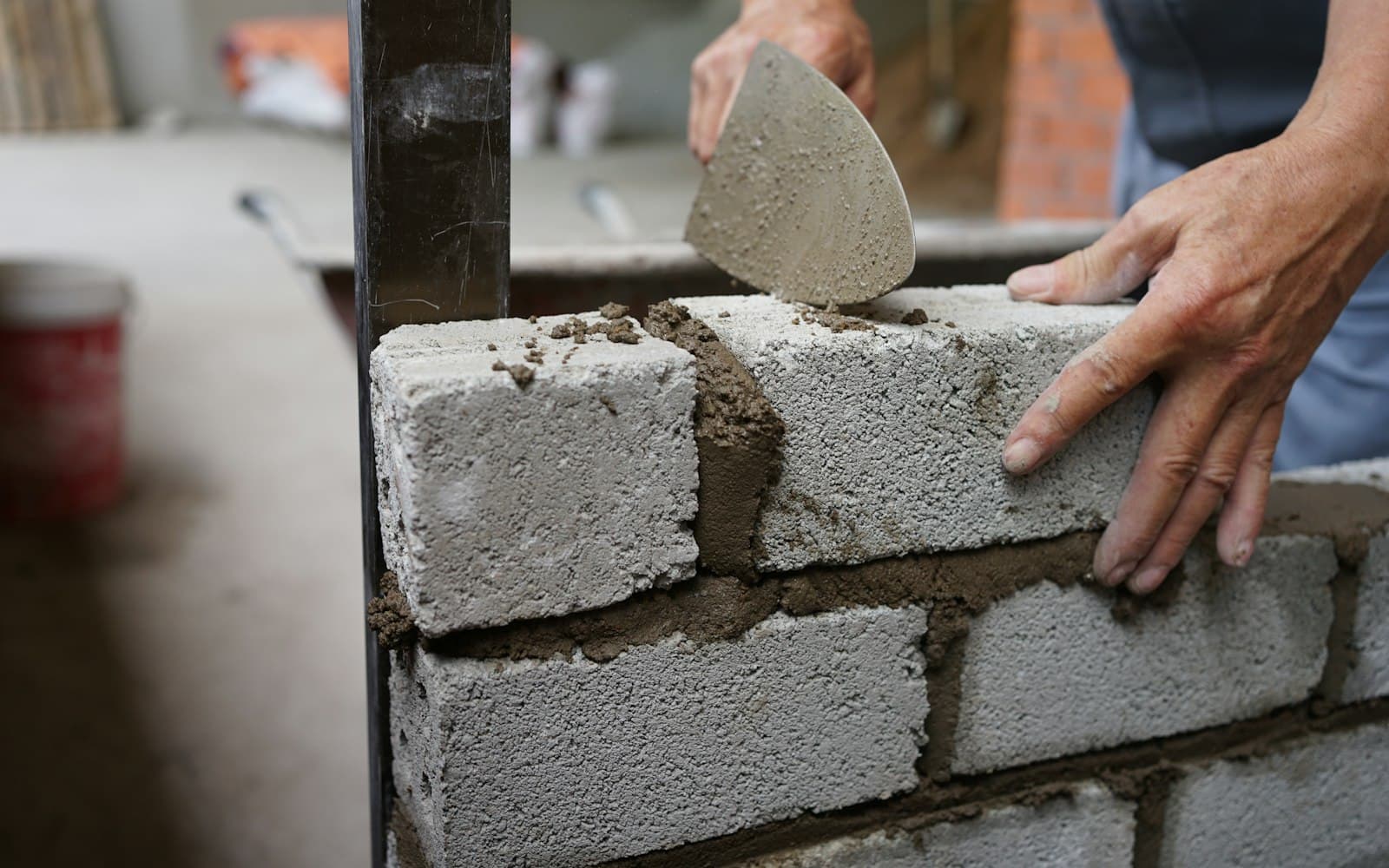 Builder laying bricks with cement